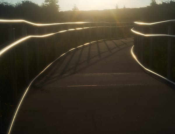 Luminous Curves at Dusk - A serene walkway is transformed by the interplay of artificial illumination and the fading natural light of the setting sun