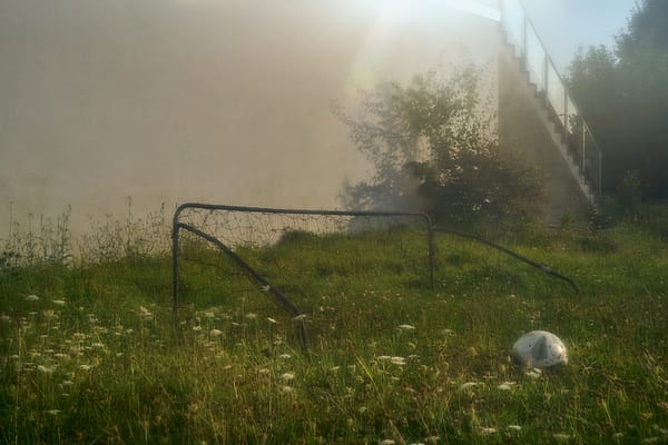 The Quiet Pitch - A serene and hazy atmosphere envelops a quiet recreational space, where the sharp geometry of sport dissolves into the soft diffusion of nature