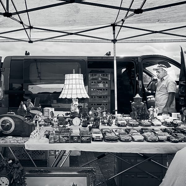 Sunday Market Shadows - A quiet tableau of commerce and memory unfolds beneath the geometric shelter of a temporary canopy