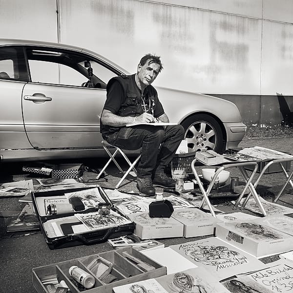 Impromptu Studio - An impromptu workspace emerges from the gray asphalt, seamlessly blending the grit of the street with the delicate, focused act of creation