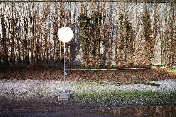 The Waiting Light - A luminous, artificial sphere punctuates a landscape of dormant vegetation and quiet industrial pause